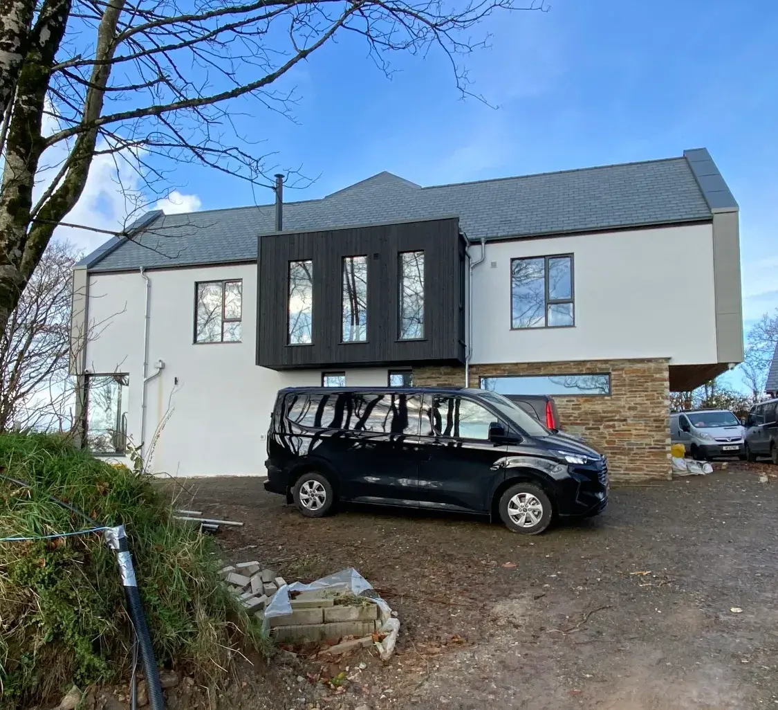 Two-storey home finished in silicone render with dark cladding and stone detailing, by PureRend